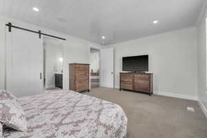 Carpeted bedroom with ornamental molding, wood ceiling, and a barn door