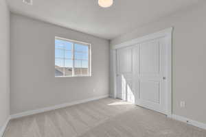 Unfurnished bedroom featuring light carpet and a closet