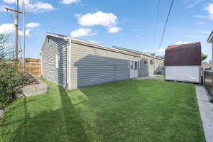 Back of property with a storage shed and a yard