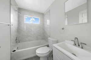 Full bathroom with tiled shower / bath, vanity, and toilet