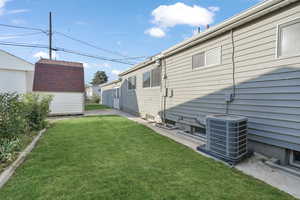 View of yard featuring central AC unit and an outbuilding