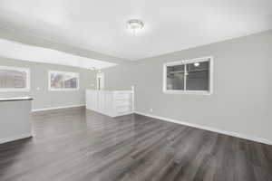 Unfurnished living room with dark wood-type flooring