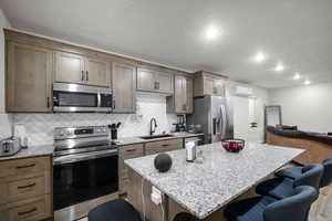 ADU Kitchen featuring a kitchen bar, a kitchen island, light stone countertops, and stainless steel appliances