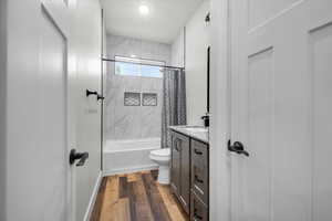 Full bathroom with vanity, shower / bath combo with shower curtain, toilet, and hardwood / wood-style flooring