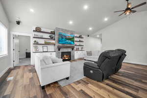 Living room with ceiling fan, lofted ceiling, a fireplace, and hardwood / wood-style floors