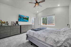 Primary Carpeted bedroom with ceiling fan and vaulted ceiling