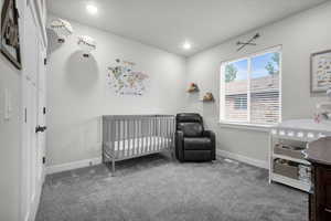 Carpeted bedroom featuring a crib