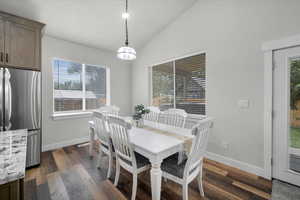 Dining area with lofted ceiling, a healthy amount of sunlight, and dark hardwood / wood-style flooring