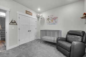 Carpeted bedroom featuring a nursery area and a closet