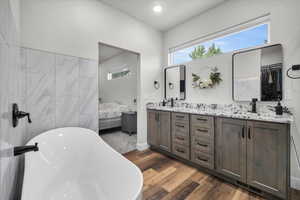 Primary Suite Bathroom with wood-type flooring, vanity, and a washtub