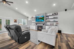 Living room featuring a tile fireplace, wood-type flooring, ceiling fan, and high vaulted ceiling