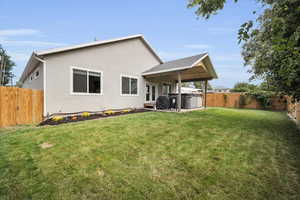 Back of house with a hot tub and a yard