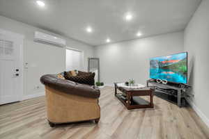 Basement Living room featuring light wood-type flooring and a wall mounted AC