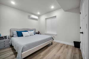 ADU Bedroom 2 with light hardwood / wood-style flooring and a wall unit AC