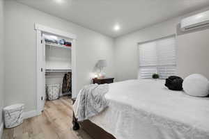 ADU Bedroom 1 with light hardwood / wood-style flooring, a closet, and an AC wall unit