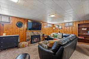 Carpeted living room featuring wood walls and a fireplace