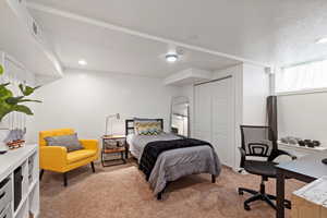 Bedroom with a closet, light colored carpet, and a textured ceiling