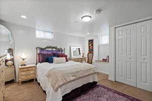 Carpeted bedroom featuring a textured ceiling and a closet