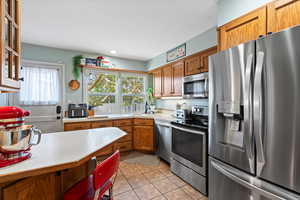 Kitchen featuring light tile patterned flooring, appliances with stainless steel finishes, and sink