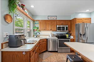 Kitchen featuring appliances with stainless steel finishes, light tile patterned floors, and sink