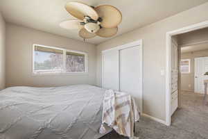 Bedroom featuring multiple windows, ceiling fan, light colored carpet, and a closet