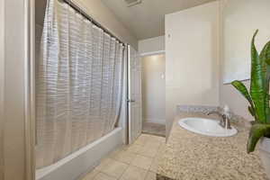 Bathroom with shower / tub combo, tile patterned flooring, and vanity