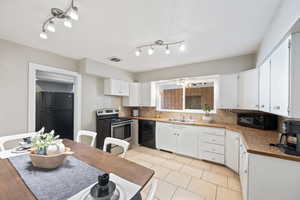 Kitchen featuring black appliances, white cabinetry, sink, and a notable chandelier