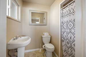 Bathroom with a shower with curtain, tile patterned floors, and toilet