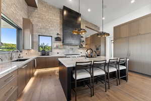 Kitchen featuring sink, a center island, tasteful backsplash, pendant lighting, and a kitchen bar