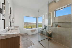 Bathroom featuring tile patterned floors, a mountain view, shower with separate bathtub, and vanity