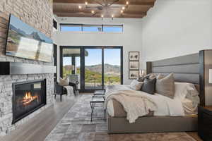 Bedroom with a mountain view, a stone fireplace, wood-type flooring, beamed ceiling, and wood ceiling