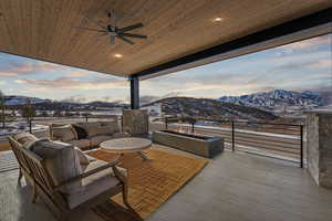 Snow covered deck featuring a mountain view, an outdoor living space, and ceiling fan