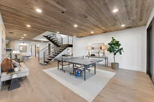 Game room with a fireplace, light hardwood / wood-style flooring, and wood ceiling