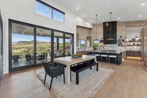 Dining room featuring a mountain view, a towering ceiling, light hardwood / wood-style flooring, and plenty of natural light