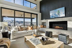 Living room featuring a stone fireplace, a mountain view, plenty of natural light, and ceiling fan