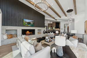 Living room with wood walls, high vaulted ceiling, light hardwood / wood-style floors, a fireplace, and beam ceiling