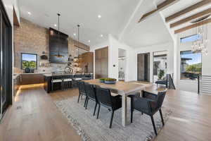 Dining space featuring a chandelier, beam ceiling, light wood-type flooring, and high vaulted ceiling