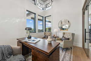 Home office featuring a towering ceiling, an inviting chandelier, and light hardwood / wood-style flooring