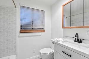 Full bathroom with tiled shower / bath, vanity, and toilet