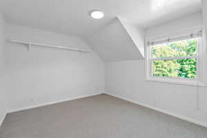 3rd upstairs bedroom featuring a textured ceiling, lofted ceiling, and carpet flooring