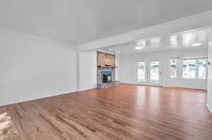 Unfurnished living room with light wood-type flooring, crown molding, a fireplace, and a textured ceiling