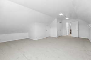 Bonus room featuring lofted ceiling and light carpet