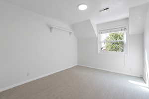 Upstairs bedroom featuring carpet and lofted ceiling