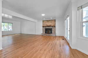 Unfurnished living room featuring a fireplace, crown molding, and light hardwood / wood-style flooring