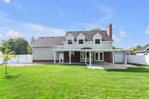 Rear view of property with a lawn and a patio, view of fruit trees