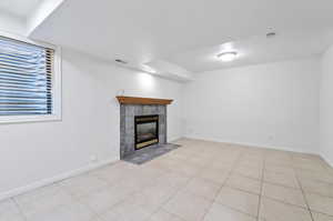 Unfurnished family room featuring a tile fireplace and light tile patterned floors