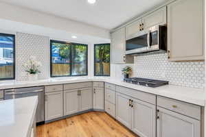 Kitchen with quartz counters, stainless steel appliances, light wood-type flooring, a center island, and double ovens. Fridge is included!