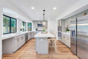 Kitchen with quartz counters, stainless steel appliances, light wood-type flooring, a center island, and double ovens. Fridge is included!