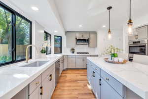 Kitchen with quartz counters, stainless steel appliances, light wood-type flooring, a center island, and double ovens. Fridge is included!