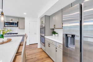 Kitchen with quartz counters, stainless steel appliances, light wood-type flooring, a center island, and double ovens. Fridge is included!